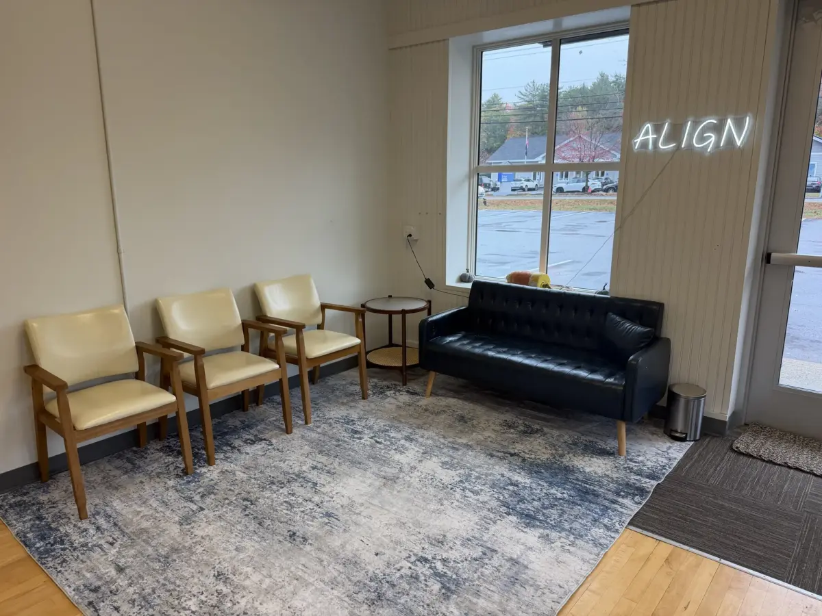 Waiting area at Elevate Chiropractic with chairs, a sofa and an ALIGN neon sign